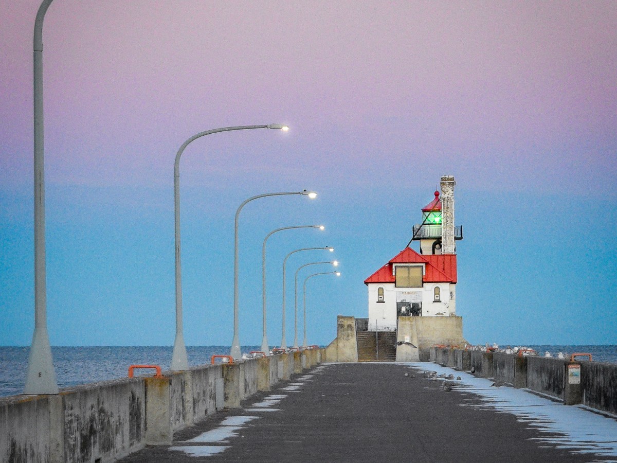Lamps flicker to life along the south pier, leading the way to the South Breakwater Light, keeping watch over the harbor.