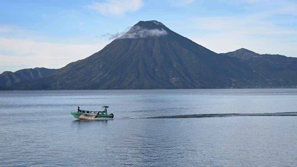 A tour boat crosses in front of Volcán San Pedro on Lake Atitlán in Guatemala