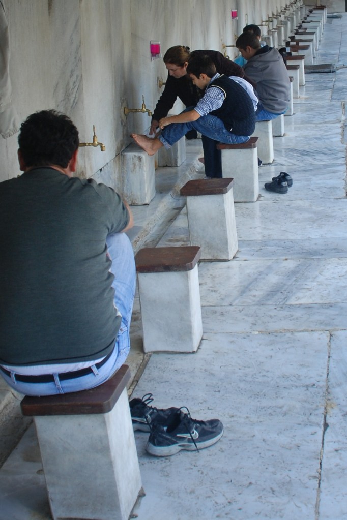 At the Blue Mosque's ablution fountain, a mother washes her son's feet in preparation for prayer.